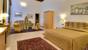 Un dormitorio amplio con una cama grande, un sofá, una silla y un armario. Hay dos cuadros en la pared, una lámpara y un cuadro.
