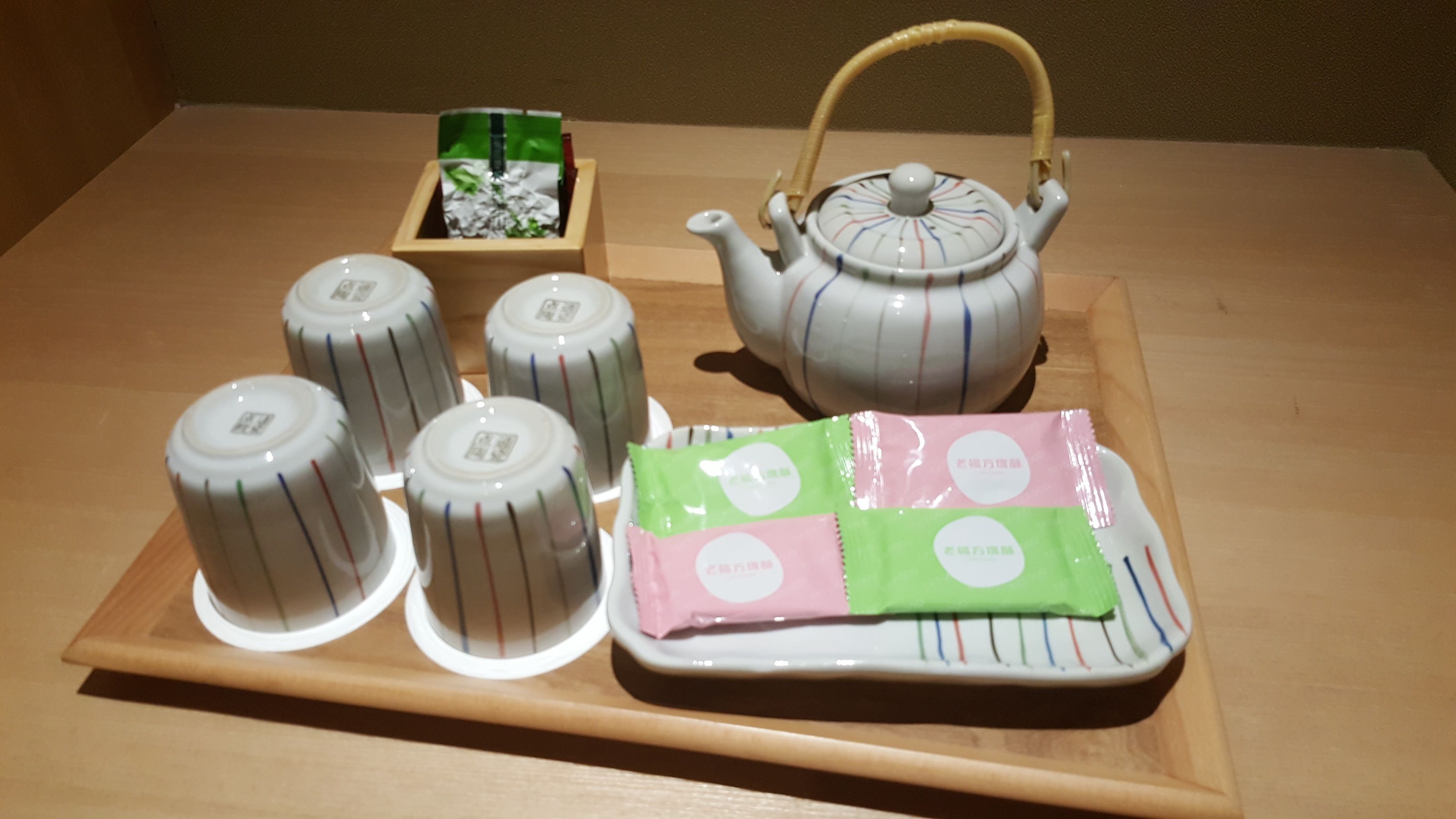 A tray with a teapot, six cups, and two packets of tea.