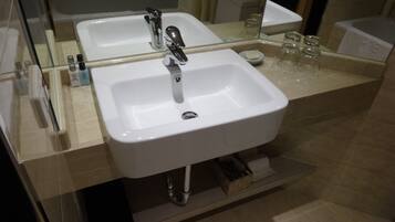 A modern bathroom with two sinks, a mirror, and a glass shower enclosure.