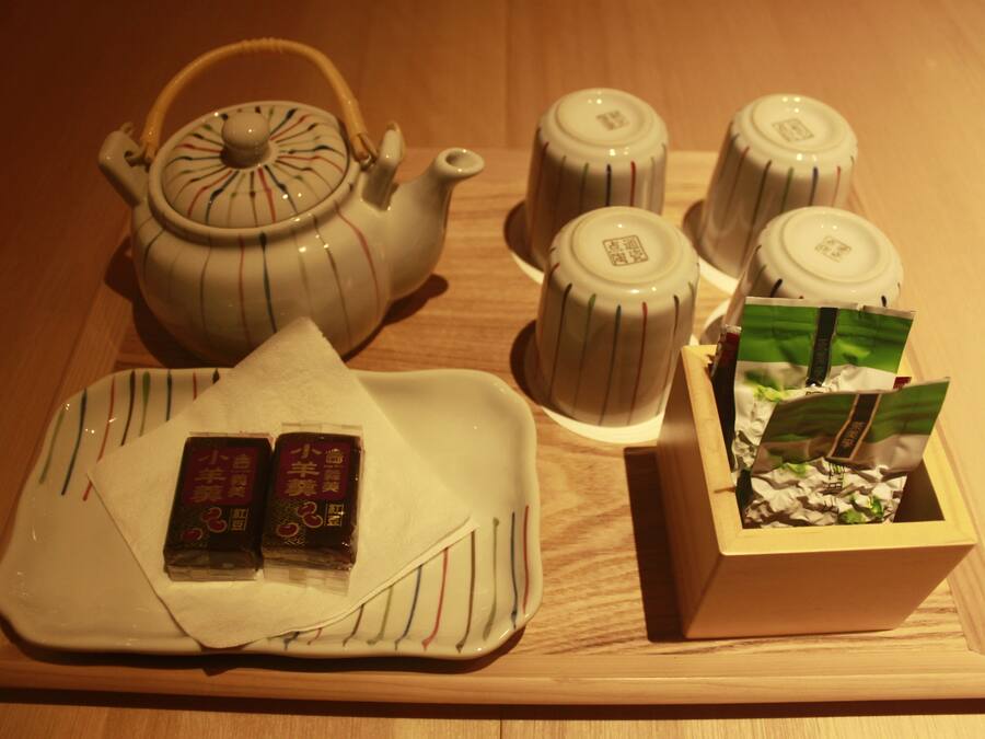 A tea set with a teapot, cups, and a tray with packaged goods.