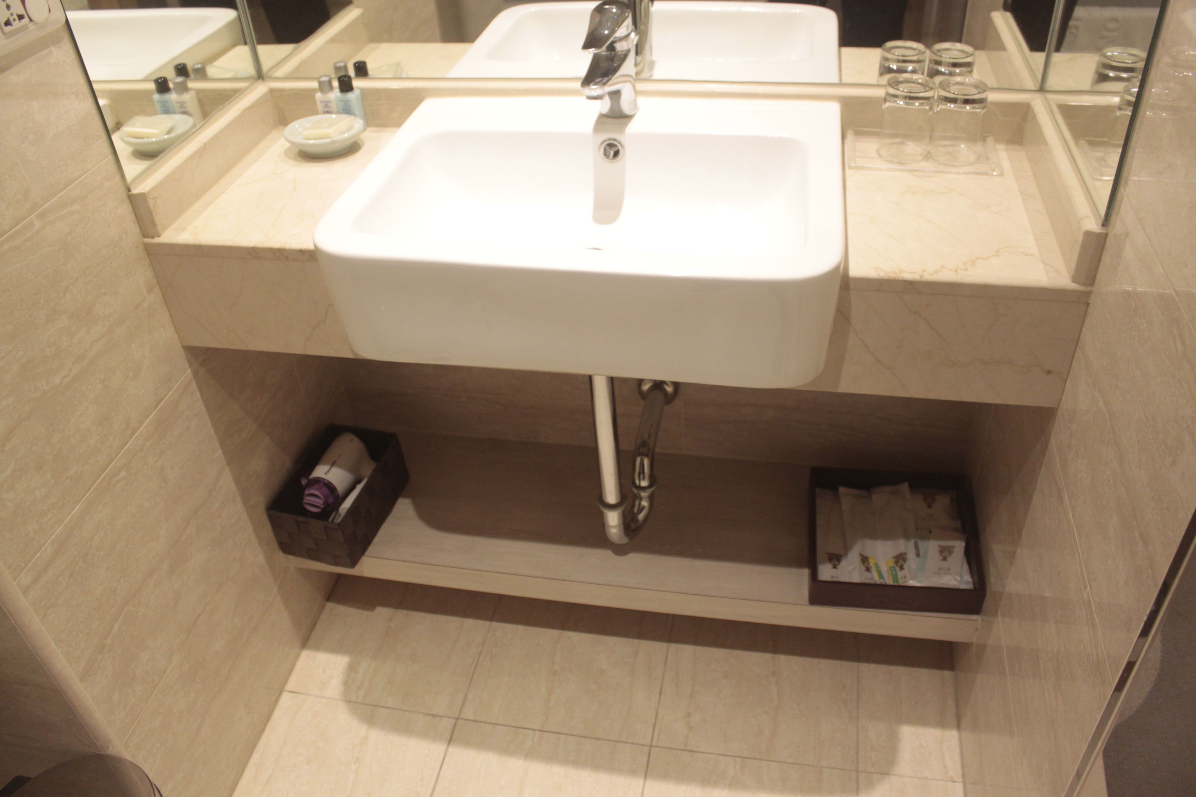 A bathroom with a white sink, mirror, and two shelves below the sink.