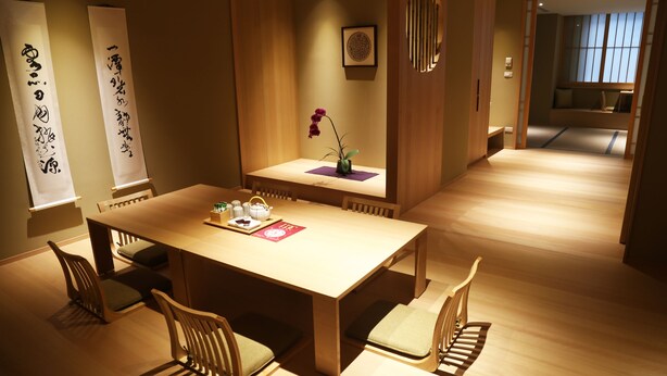 A traditional Japanese-style dining room with a wooden table and chairs, a vase with a single purple orchid, and two vertical scrolls with calligraphy on the walls. - Maison de Chine Hotel Chiayi (Chiayi City)