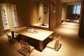 A traditional Japanese-style dining room with a wooden table and chairs, a vase with a single purple orchid, and two vertical scrolls with calligraphy on the walls. - Maison de Chine Hotel Chiayi (Chiayi City)