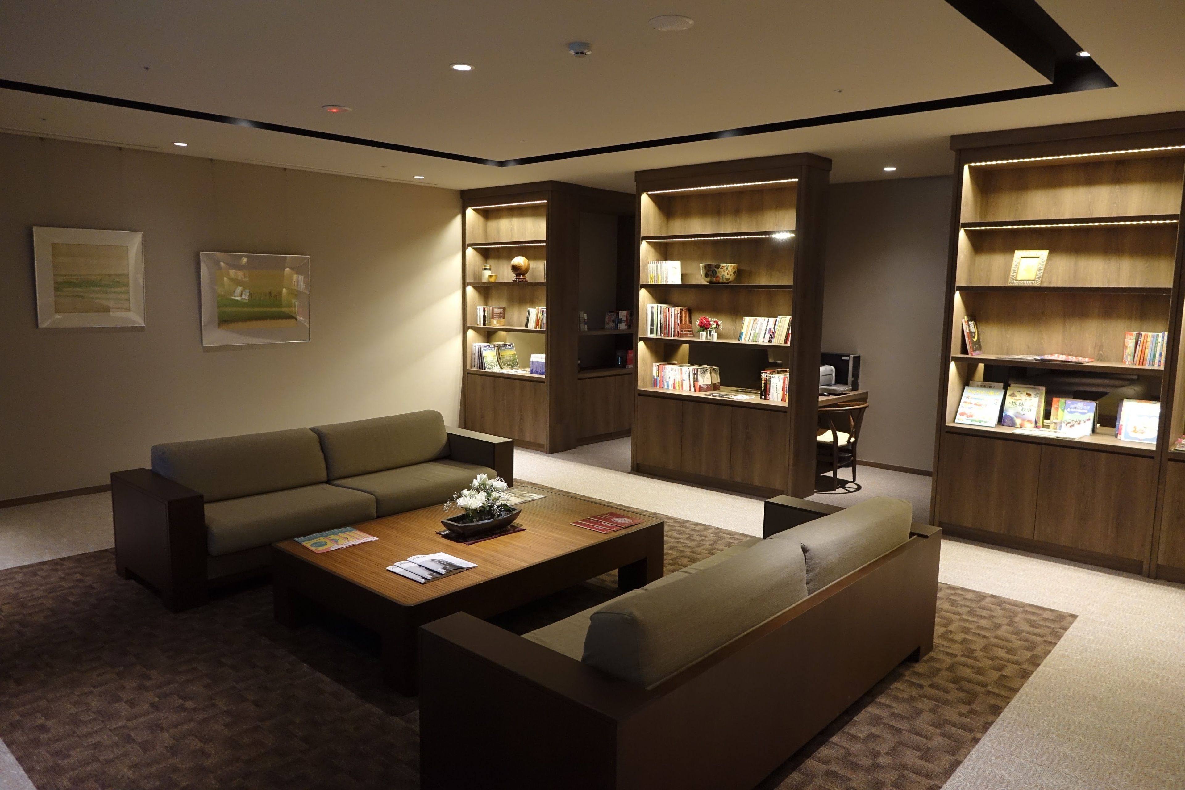 A modern living room with a sectional sofa, a coffee table, and built-in bookshelves.