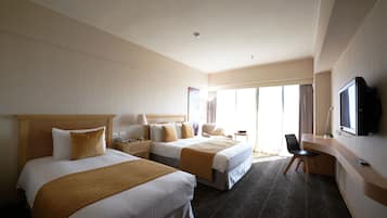 A hotel room with two beds, a desk, a chair, a television, and a large window with curtains.