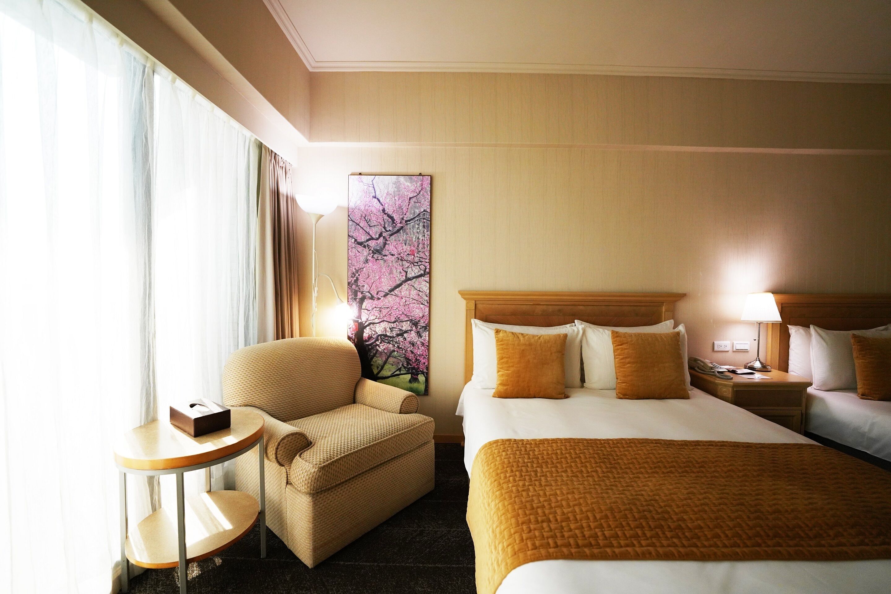 Une chambre d’hôtel avec un grand lit, une chaise, une petite table et un tableau au mur.