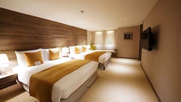 A hotel room with two beds, wooden headboard, bedside lamps, and a TV on the wall.