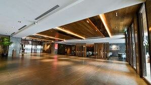 A spacious lobby with a modern design, featuring a high ceiling with wooden panels and recessed lighting. - Maison de Chine Hotel Chiayi (Chiayi City)