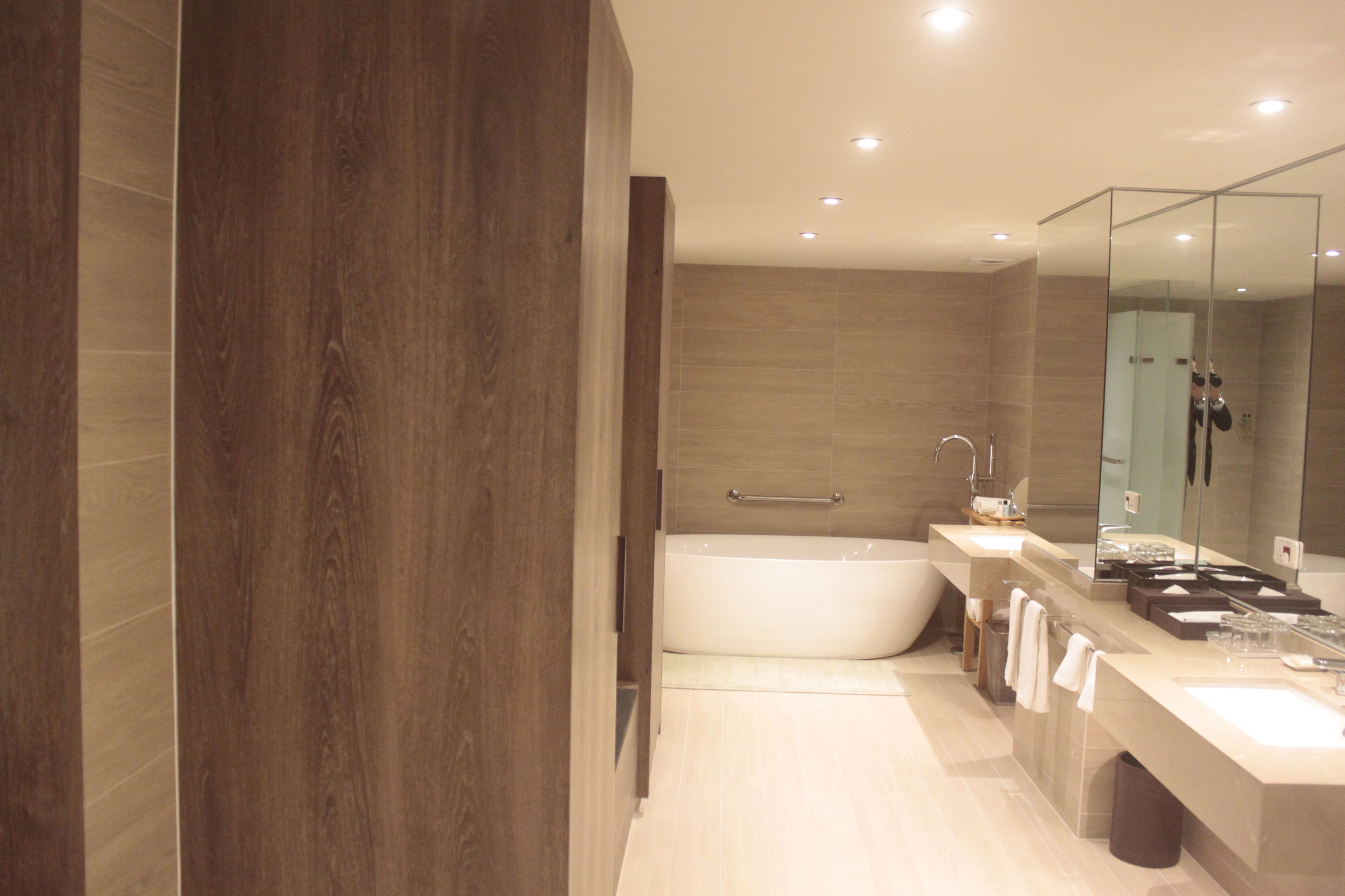 Un baño moderno con un espejo grande, una bañera y un tocador con lavabo.