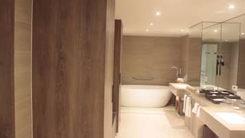 Un baño moderno con un espejo grande, una bañera y un tocador con lavabo.