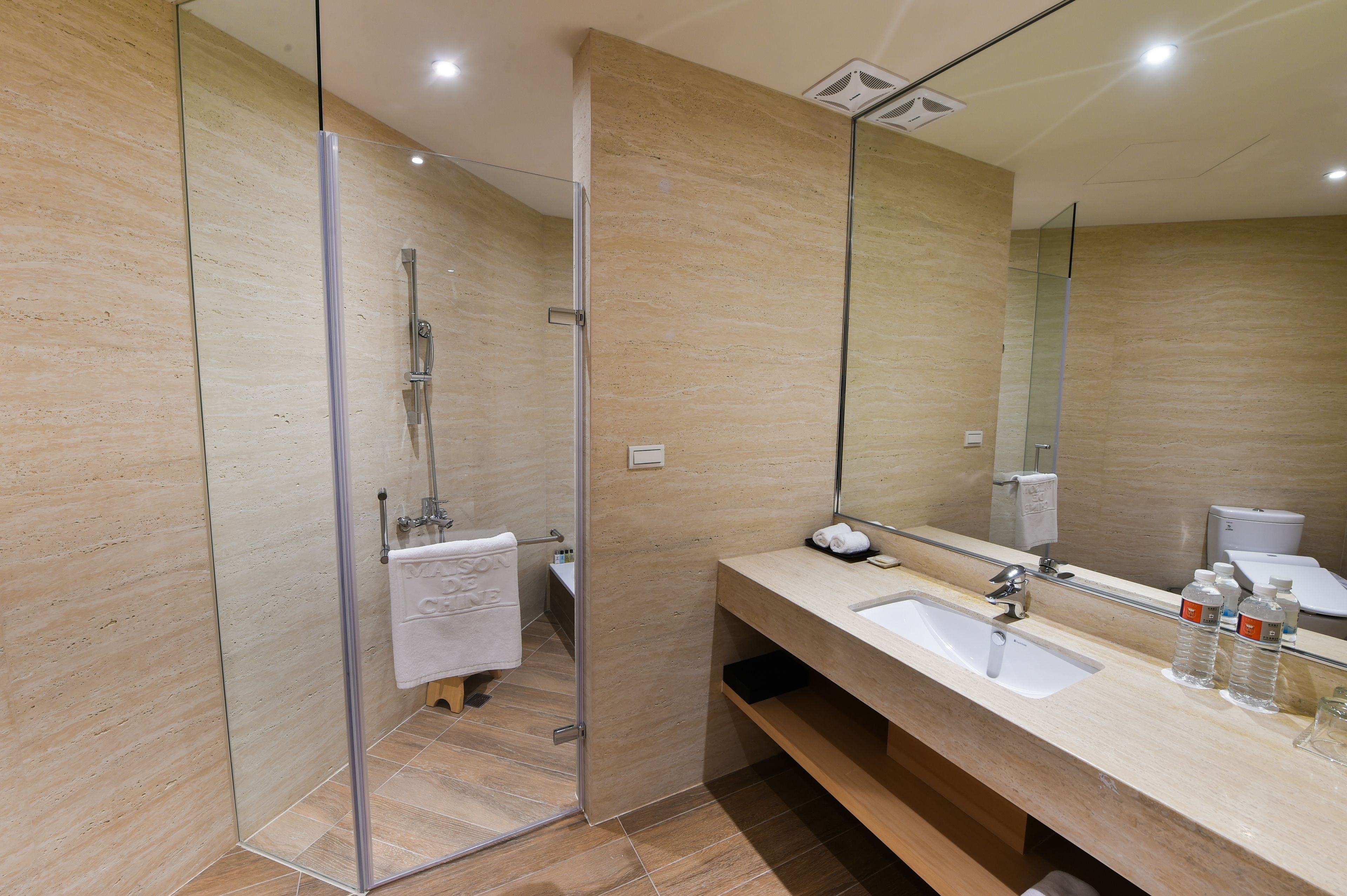 A modern bathroom with a glass shower enclosure, a large mirror, and a vanity with two sinks.