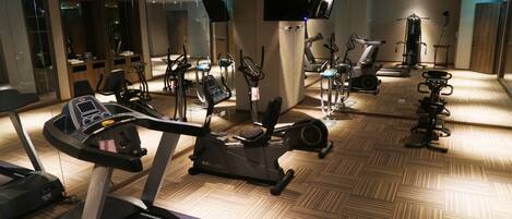 A gym with various exercise equipment including treadmills, stationary bikes, and elliptical machines.