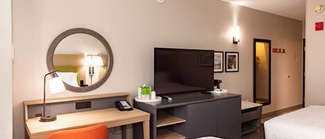 Habitación de hotel con escritorio, silla, televisión y dos camas.