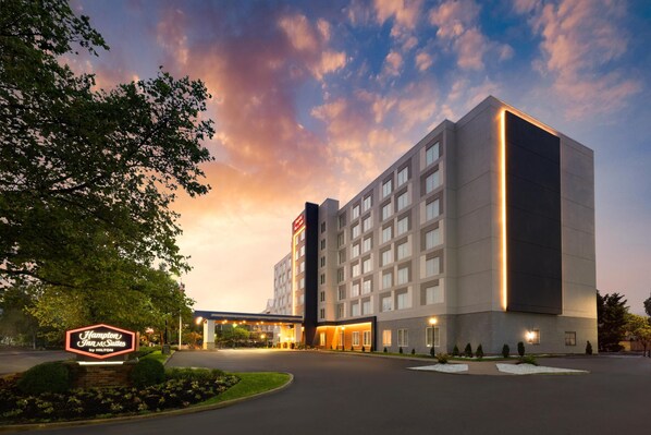 A large, modern hotel with a prominent sign for Hampton Inn & Suites by Hilton.
