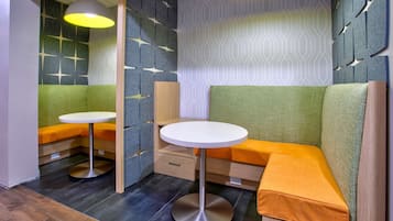Un área de estar moderna con una mesa redonda, bancos acolchados y paredes con diseño.