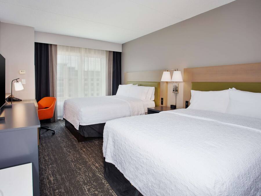 Una habitación de hotel con dos camas, un escritorio, una silla y un televisor.