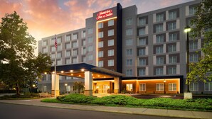 A modern hotel with a prominent sign, multiple floors, and a well-lit entrance.