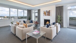 A modern living room with a sofa set, a glass coffee table, and a fireplace.