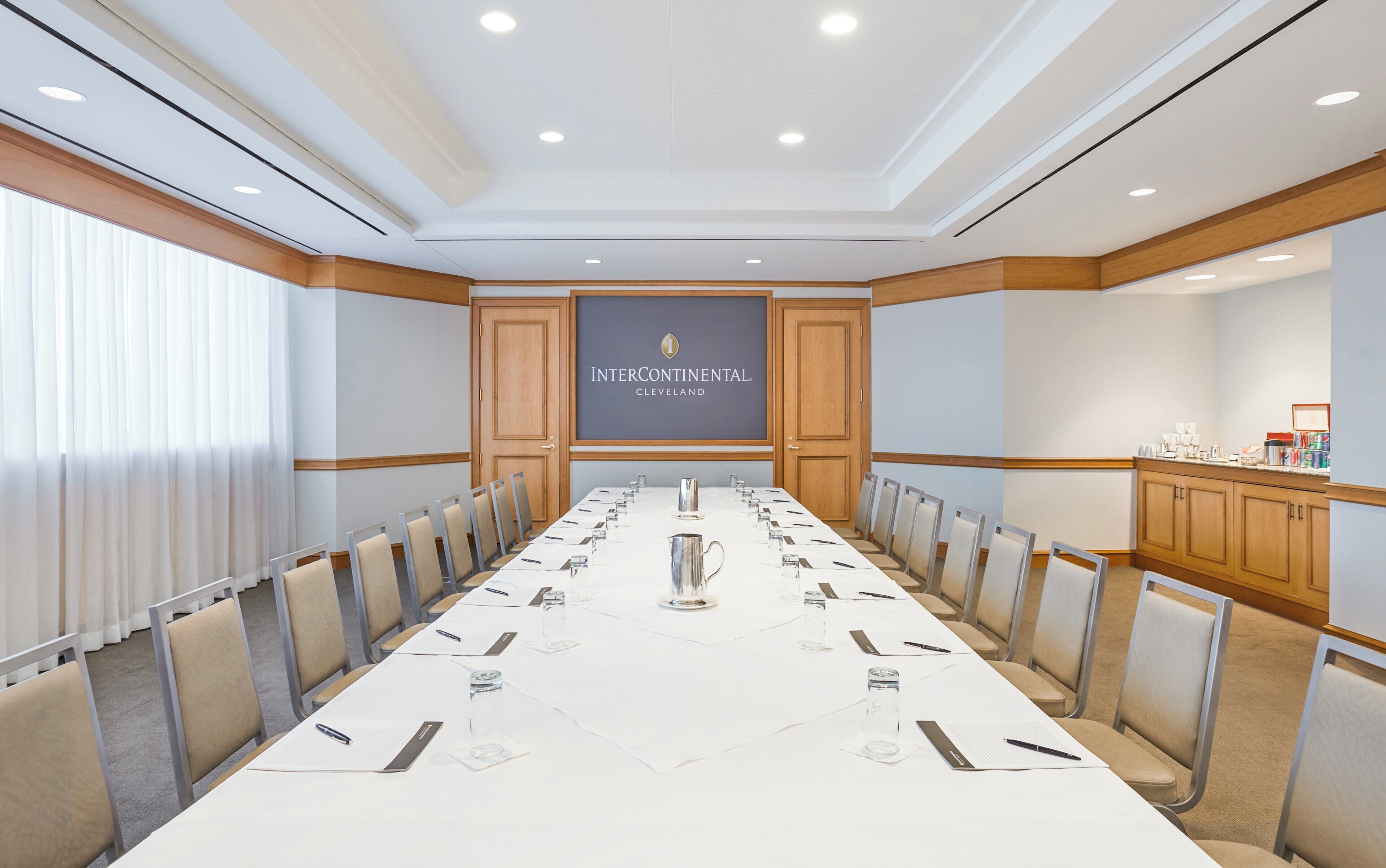 Un salón de conferencias con una larga mesa, sillas, un atril y un cartel con el texto 'Intercontinental Cleveland'.