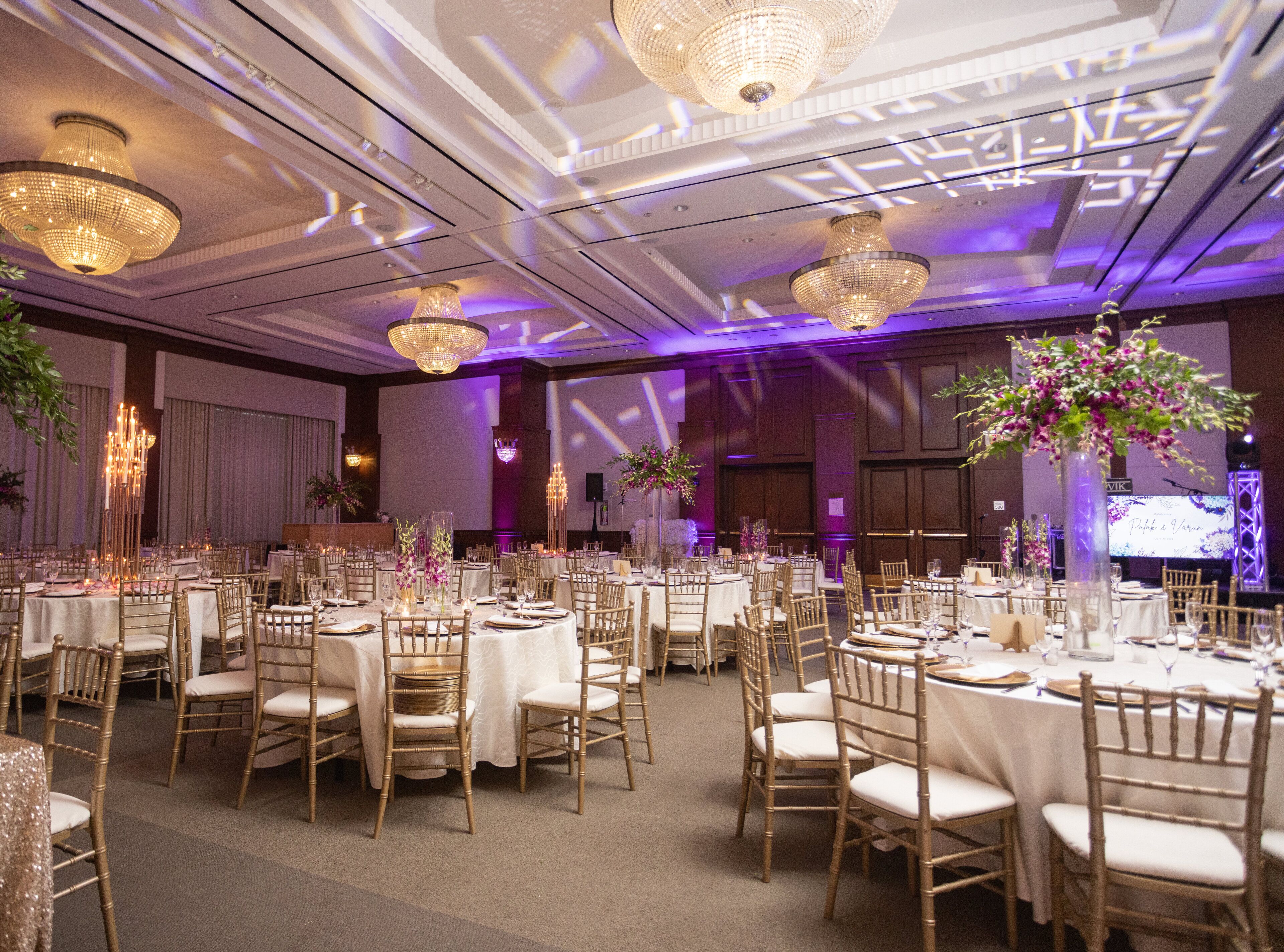 Un salón de banquetes con mesas redondas, sillas doradas y candelabros.