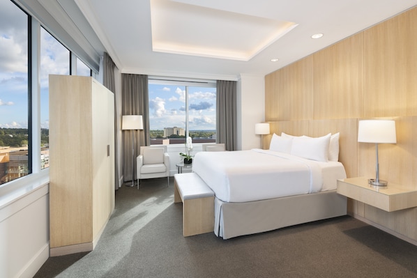 A modern hotel room with a large bed, bedside tables, a desk, and a view of the city. - InterContinental Cleveland by IHG (Cleveland)