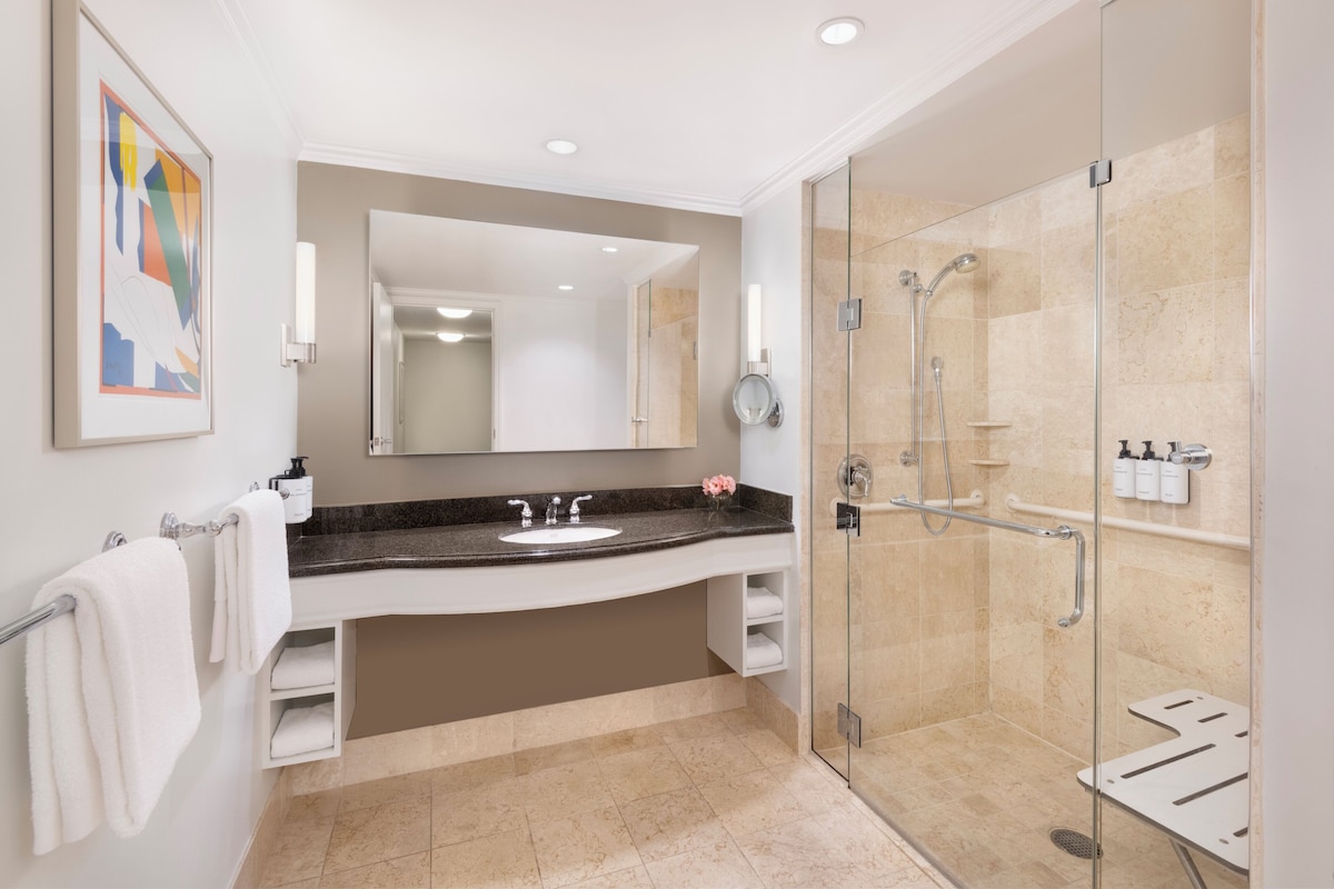 A modern bathroom with a large mirror, a sink, and a walk-in shower.