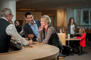 A modern indoor setting with a round table, people seated, and a bar area. - InterContinental Cleveland by IHG (Cleveland)