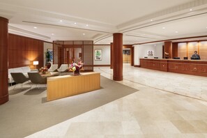 A spacious lobby with a reception desk, seating area, and a large wooden reception counter.