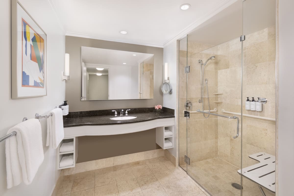 A modern bathroom with a large mirror, a sink, and a walk-in shower.