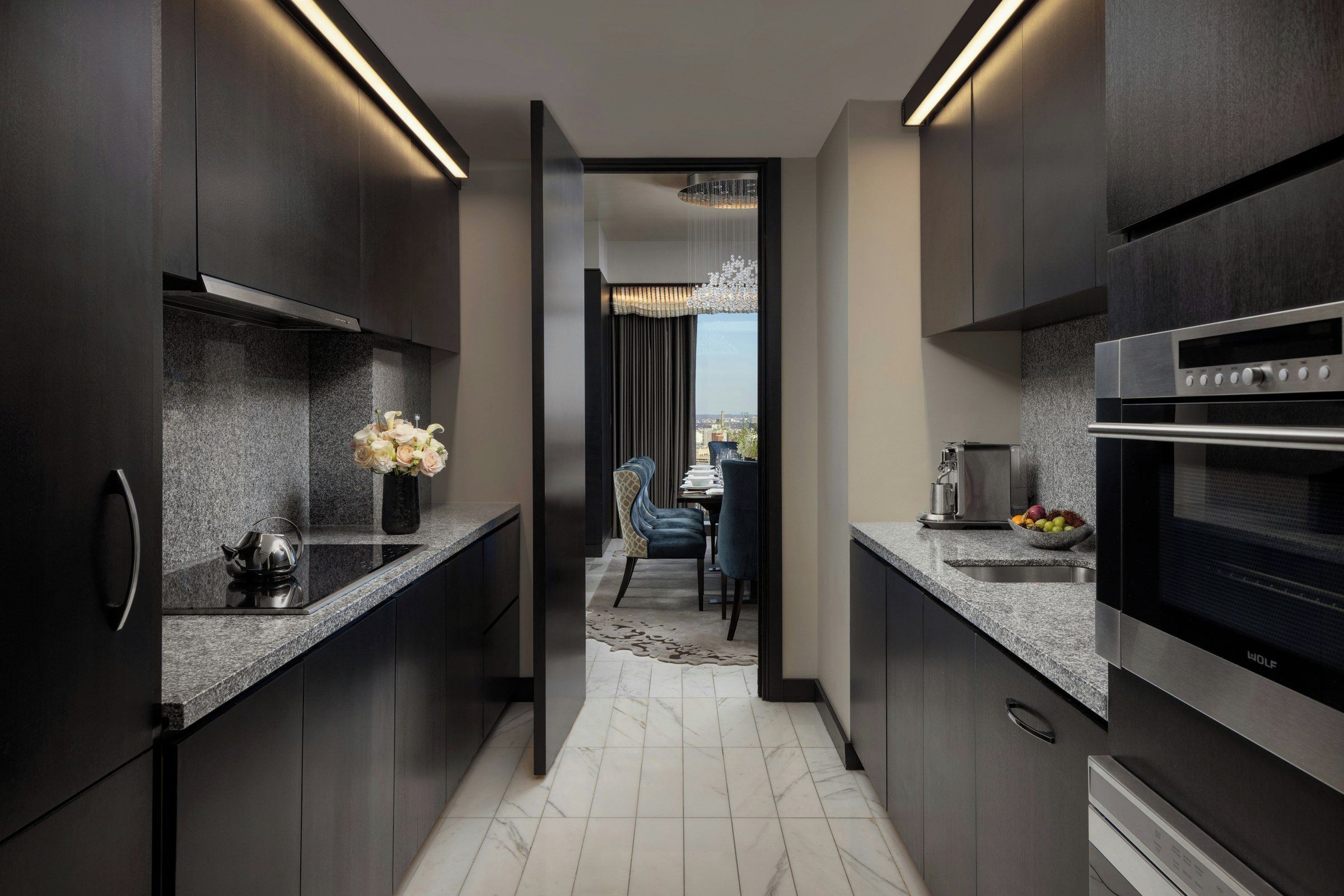 A modern kitchen with dark cabinetry, granite countertops, and stainless steel appliances.