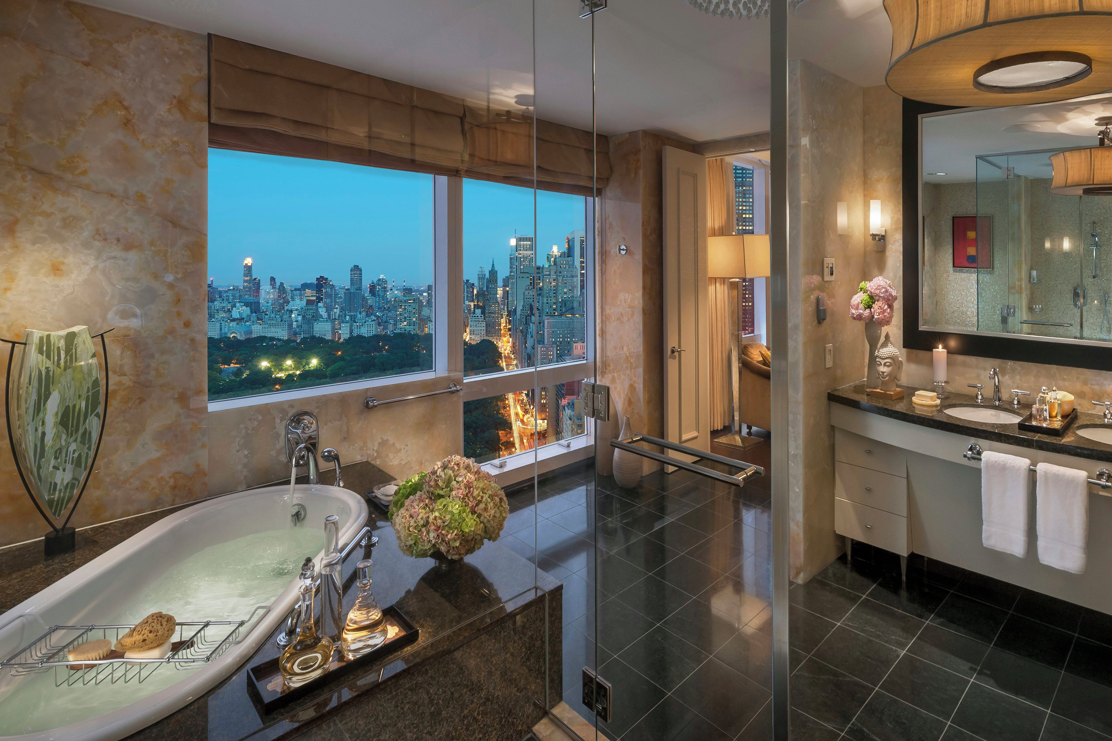 Un baño moderno con bañera, un espejo grande y vistas a la ciudad.