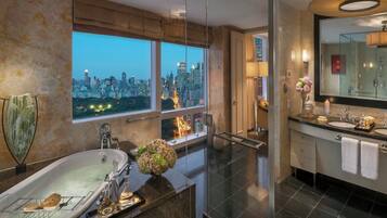 Un baño moderno con bañera, un espejo grande y vistas a la ciudad.