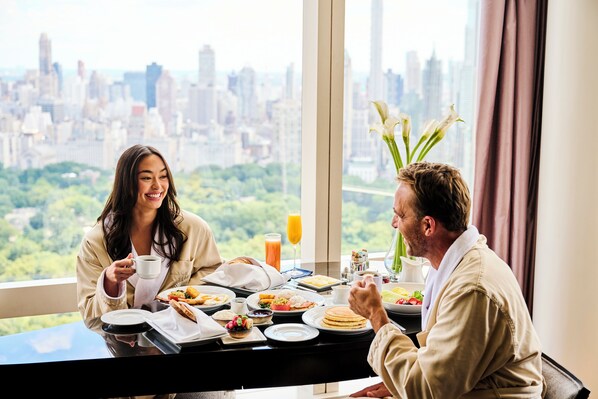 Un desayuno con vista a la ciudad, que incluye una mesa con platos de comida, una taza de café y un florero con flores.