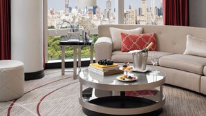 A modern living room with a city view, a round glass coffee table, and a sofa with a red pillow.