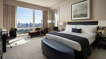 Une chambre d’hôtel avec un grand lit, un bureau, une chaise, un canapé et une vue sur la ville.