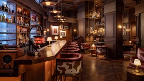 A bar area with a long counter, leather barstools, and shelves of bottles. - Mandarin Oriental, New York (New York)