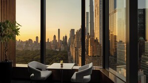 A modern room with a city view, a round table, two chairs, and a potted plant. - Mandarin Oriental, New York (New York)