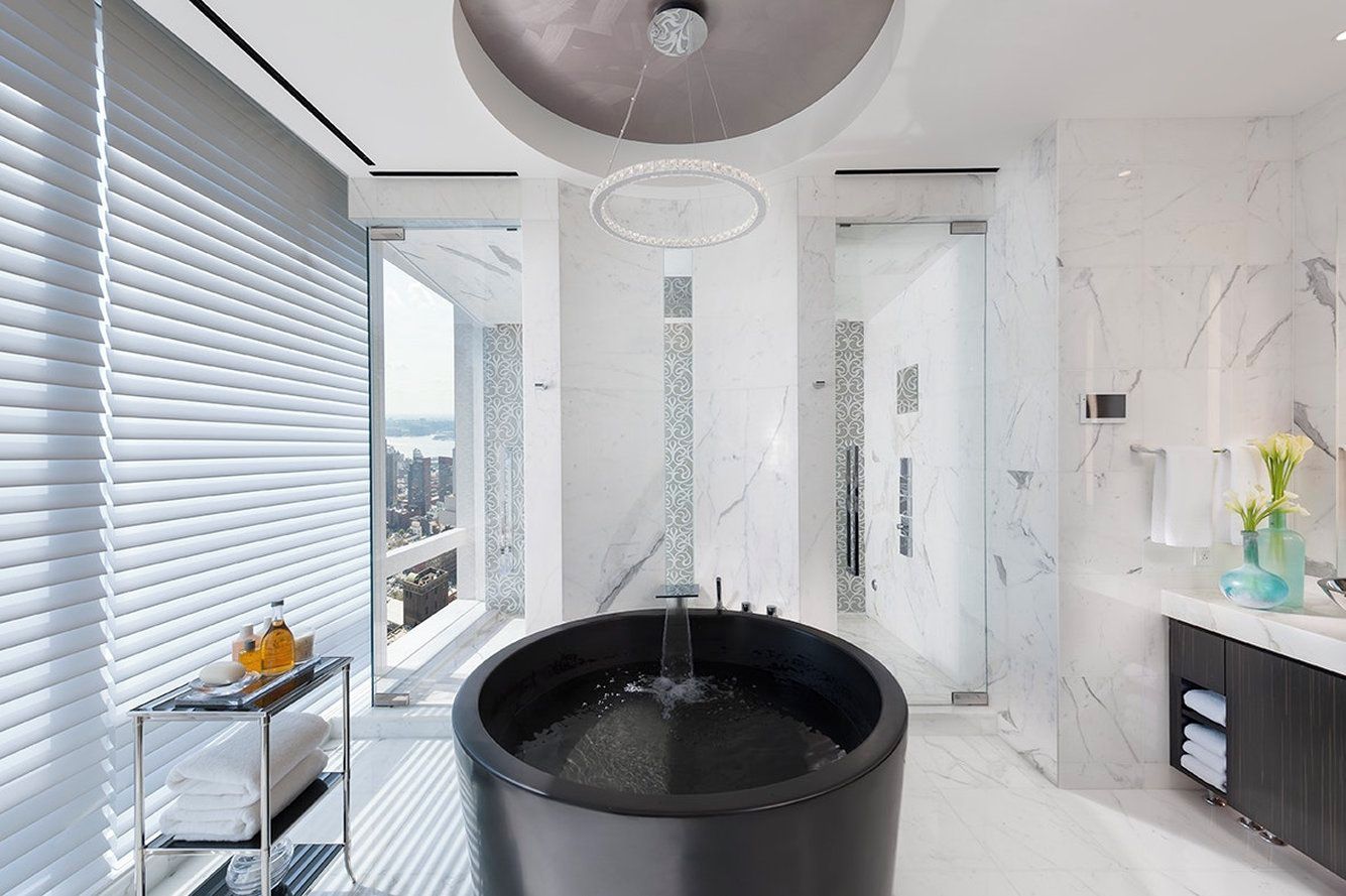 Un bagno moderno con una vasca da bagno ampia, una cabina doccia in vetro e un mobile con piano in marmo.