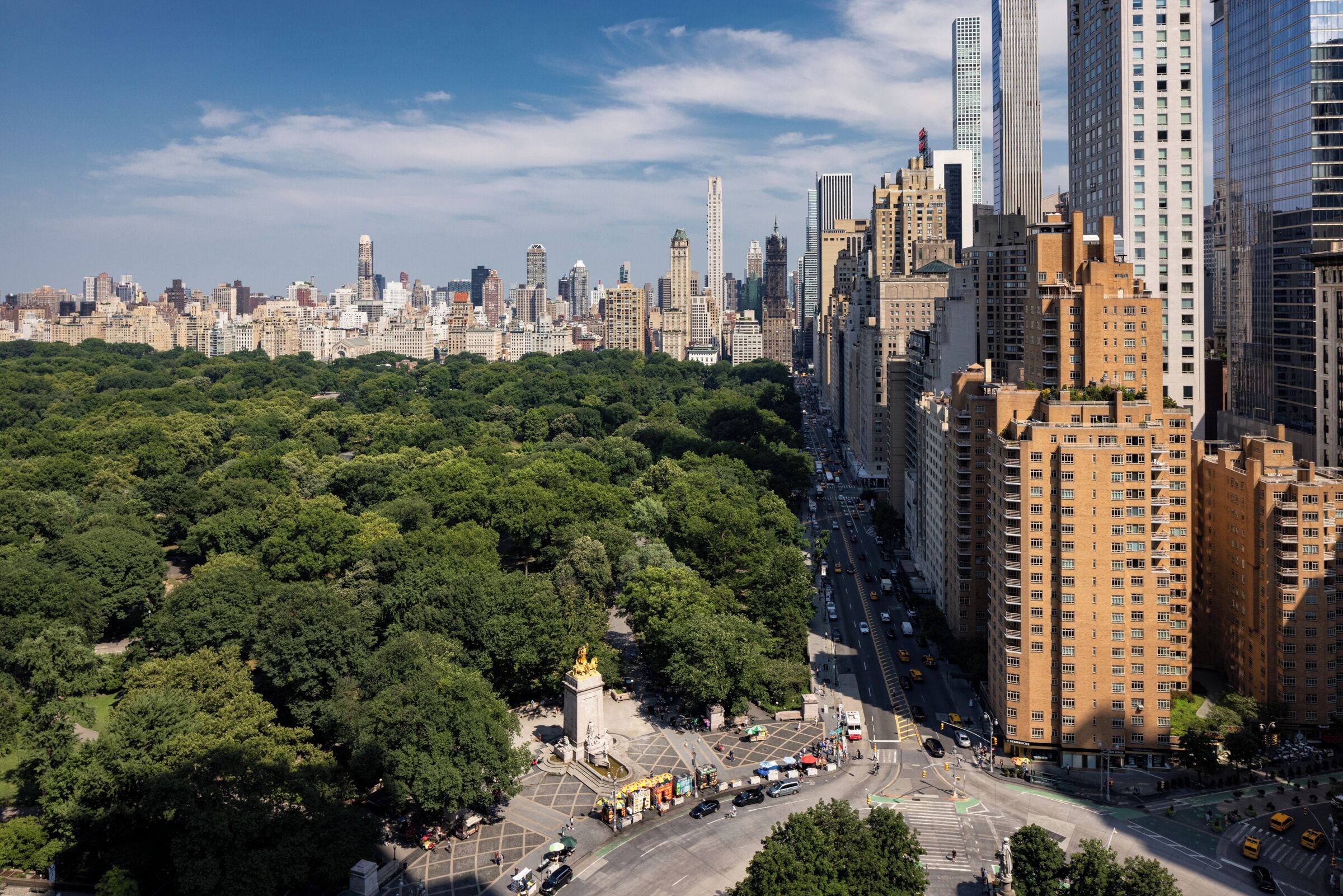 Un paisaje urbano con edificios densos, un amplio parque verde y un monumento.