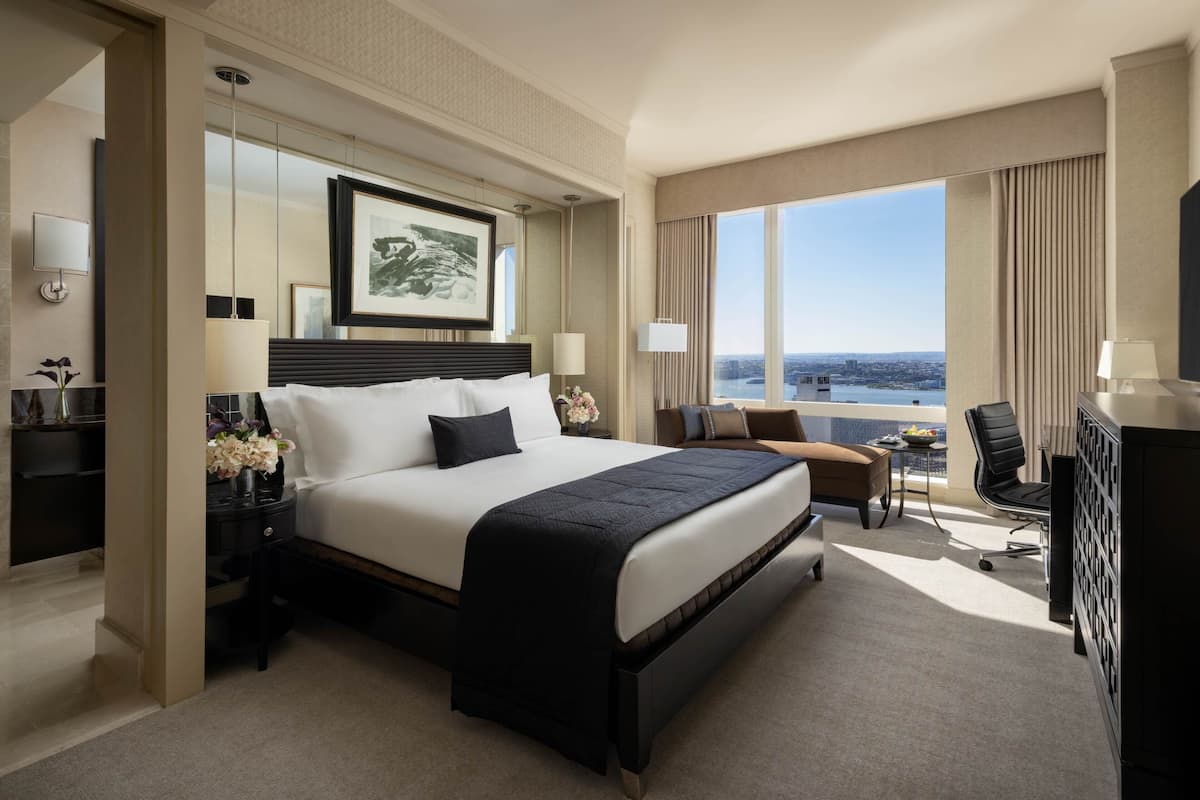 Een hotelkamer met een groot bed, een bureau, een stoel en uitzicht op de stad.