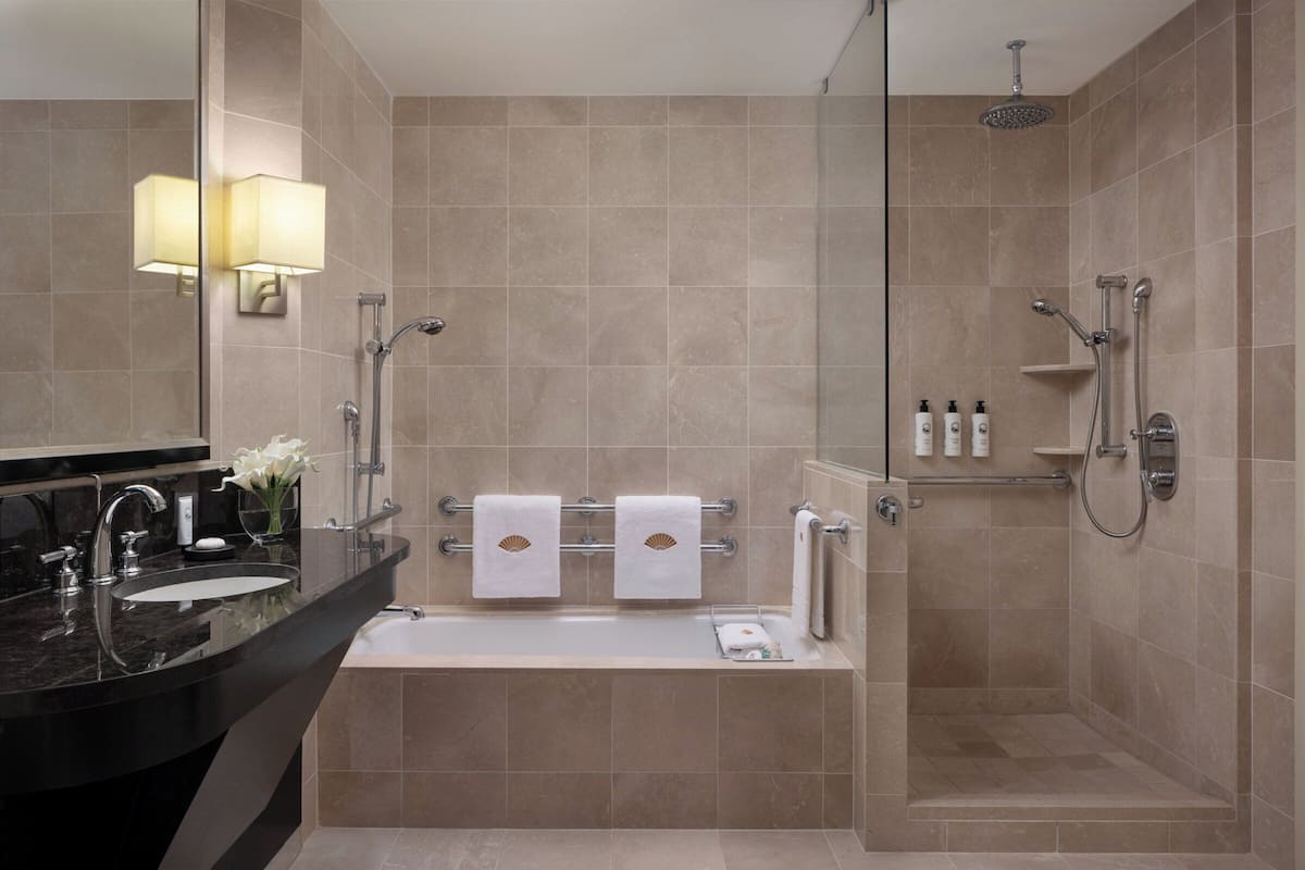 A modern bathroom with a bathtub, a shower, and a vanity with a sink.