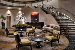 A lobby with a central seating area, a staircase, and a reception desk.