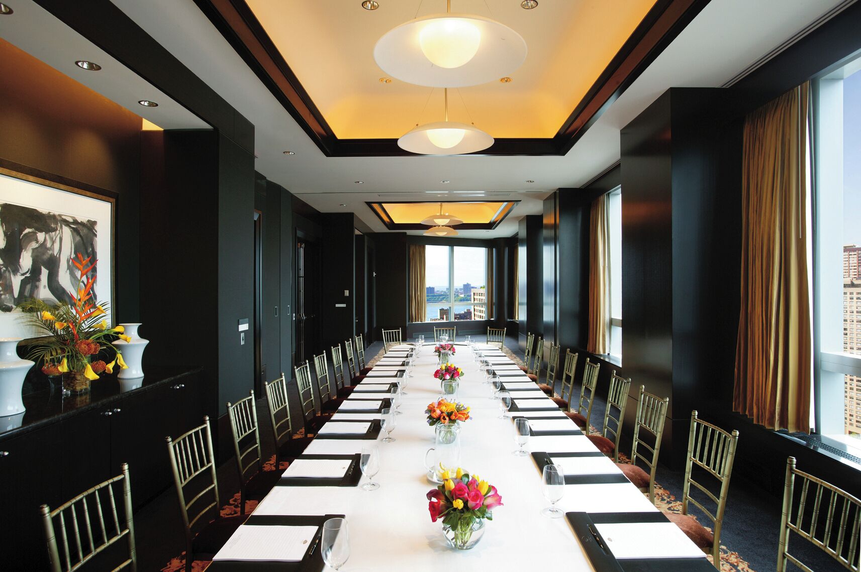 A long conference room with a white table, chairs, and floral centerpieces.