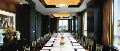 A long conference room with a white table, chairs, and floral centerpieces.