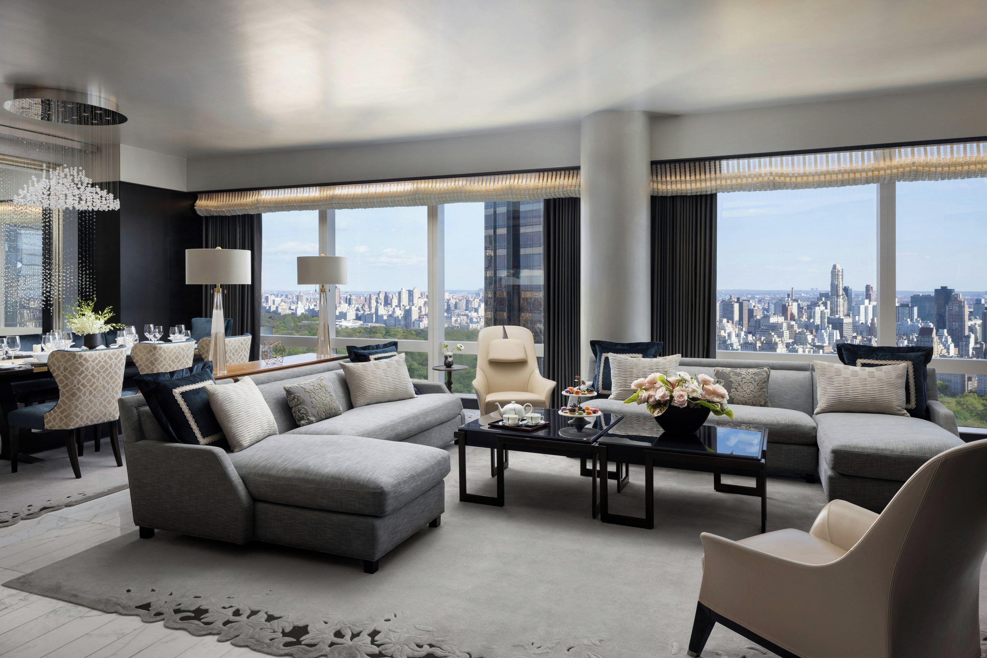 A modern living room with a sectional sofa, a coffee table, and a view of a cityscape through large windows.