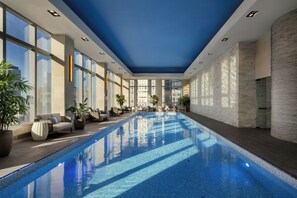 A modern indoor swimming pool with clear blue water, surrounded by lounge chairs and potted plants. - Mandarin Oriental, New York (New York)