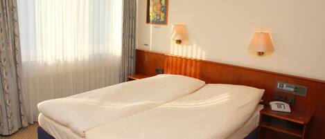 Une chambre d’hôtel avec un lit double, deux lampes de chevet, un téléphone et un tableau au mur.