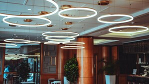 Un interior moderno con luces circulares en el techo, paneles de madera y una zona de bar.