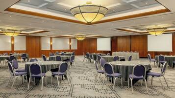 A conference room with round tables, chairs, and a large screen.