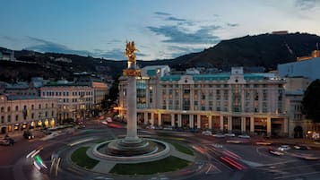Stunning hotel with a grand entrance, ornate column, and beautifully manicured gardens.
